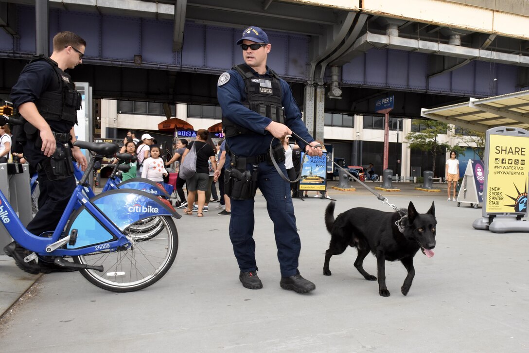 Petty Officers 2nd Class Steven Suhey, right, and Caden Collins and Cappy, a military explosive detection dog, conduct security sweeps at the Ferry Pier 11-Downtown Manhattan.