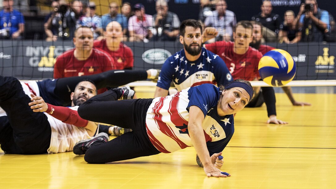An Army veteran dives for a ball during a sitting volleyball match.