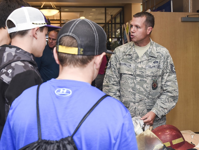 U.S. Air Force Tech Sgt. Jayton Washington, 312th Training Squadron instructor, explains how the various layers of their fire jackets protect firefighters from extreme heat during the Annual Business Expo in San Angelo, Texas, at the McNease Convention Center, Sept. 27, 2017. Washington described how the jacket weighs 22lbs and their combined gear weighs 110lbs. (U.S. Air Force photo by Aryn Lockhart/Released)