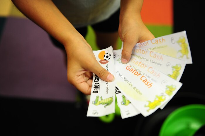 Briana Miller shows off the gator cash she earned for participating in Day for Kids at the Joint Base Charleston Weapons Station Youth Center Sept. 21, 2017