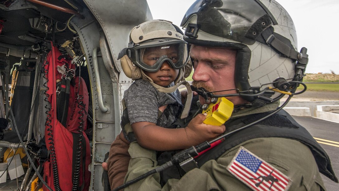 A sailor holds a child after a helicopter transported them.