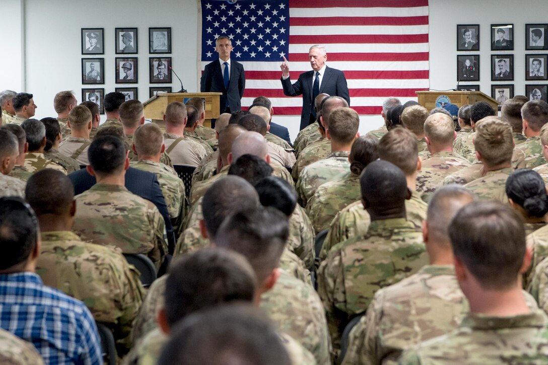 Defense Secretary Jim Mattis and the NATO secretary general talk to seated service members.