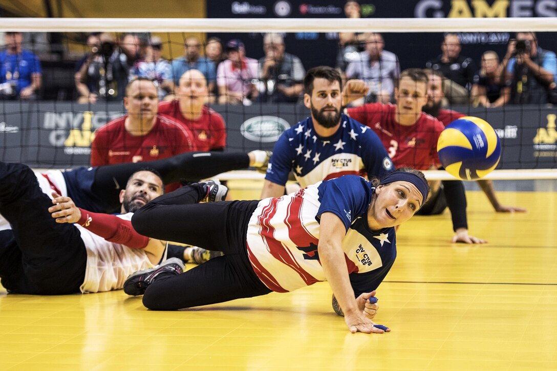 An Army veteran dives for a ball during a sitting volleyball match.