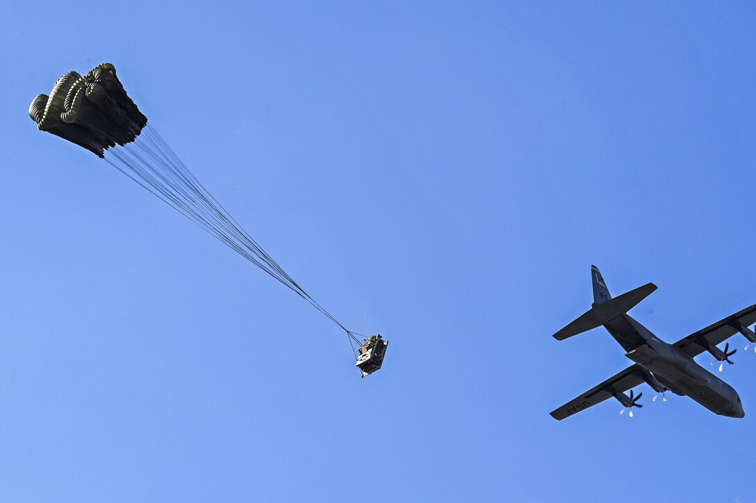 A Humvee attached to a parachute descends to a drop zone in Italy.