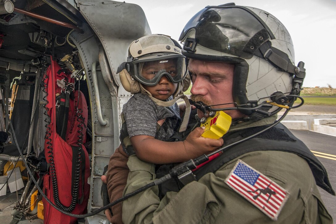 A sailor holds a child after a helicopter transported them.