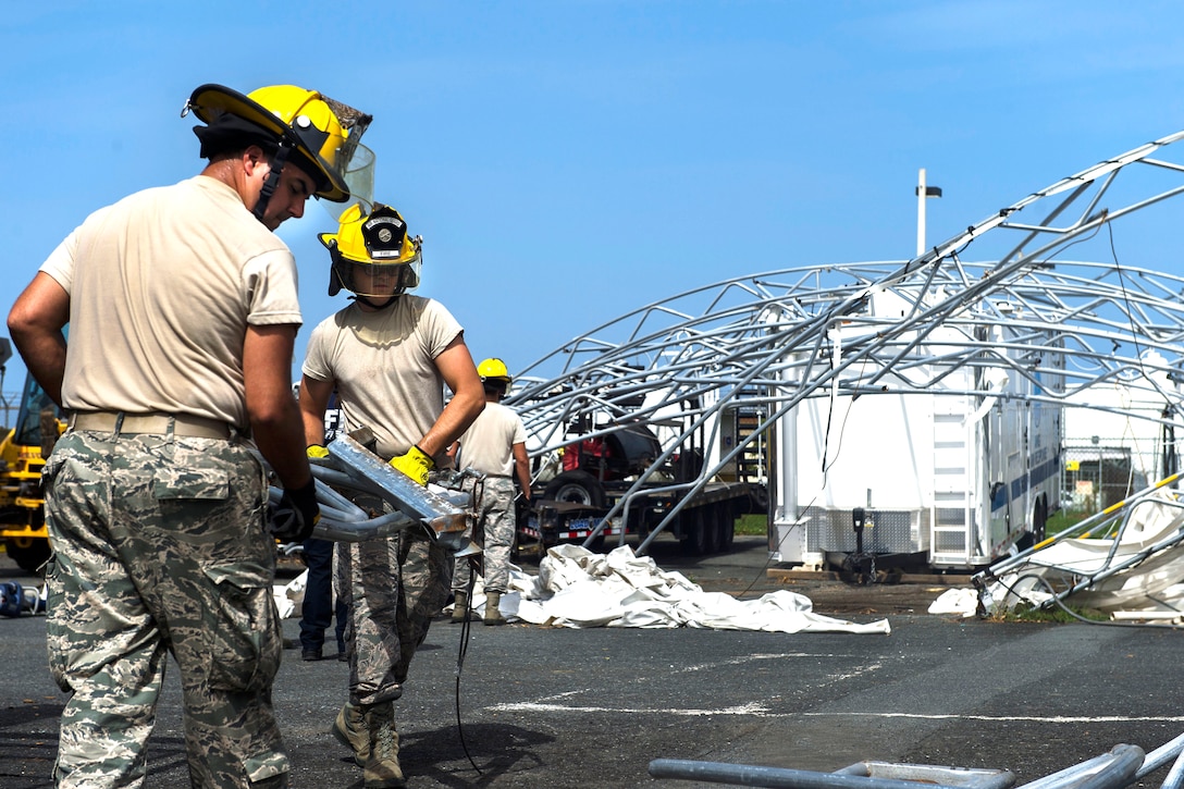 Airmen pick up pieces of debris.