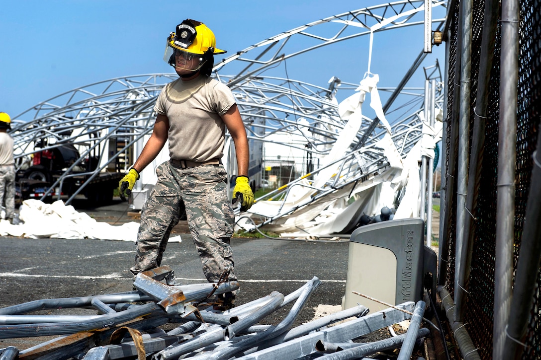 An airman stands near a pile of debris.