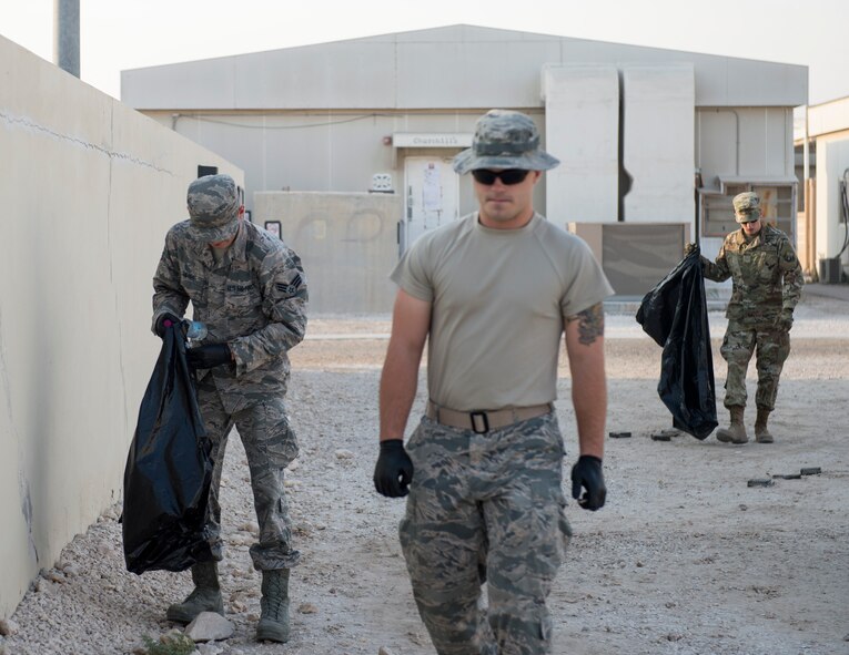 U.S. Air Force Senior Airman Zachery Dwyer, left, sub-committee lead for Operation Community with the First 4 professional organization, Airman 1st Class Austin Zudel, center, a cable and antenna systems technician with the 379th Expeditionary Communication Squadron and Senior Airman Justin Ginnell, emergency management specialist with the 379th Expeditionary Civil Engineer Squadron, pick up trash during a base cleanup at Al Udeid Air Base, Qatar, Sept. 1, 2017.