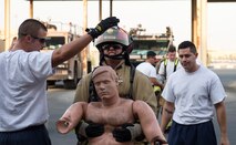 U.S. Air Force Staff Sgt. Brett Aldrich, center, a firefighter with the 379th Expeditionary Civil Engineer Squadron’s Fire and Emergency Services Flight, carriers a 175-pound mannequin to the finish line of a firefighter combat challenge at Al Udeid Air Base, Qatar, Sept. 1, 2017.