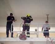 A firefighter with the Qatar Emiri Air Force Fire Department, Al Udeid Air Base, center, completes the hose hoist station during a firefighter combat challenge at Al Udeid Air Base, Qatar, Sept. 1, 2017.