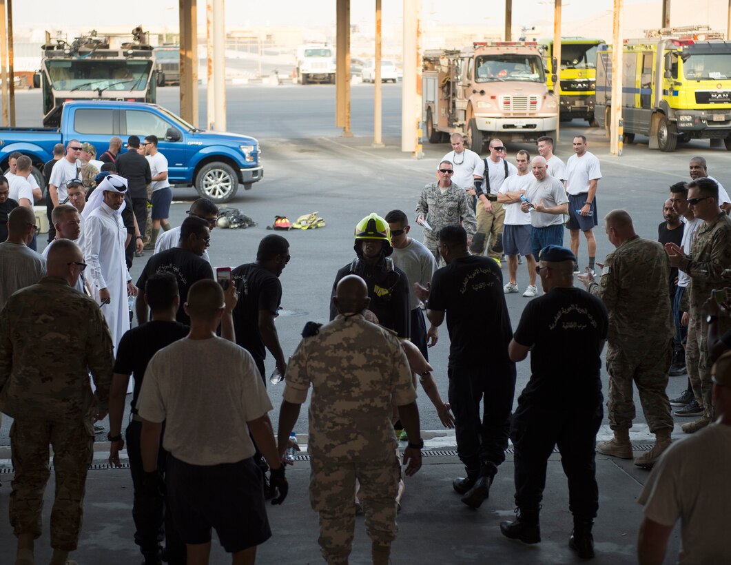 A firefighter with the Qatar Emiri Air Force Fire Department, Al Udeid Air Base, center, carriers a 175-pound mannequin to the finish line of a firefighter combat challenge at Al Udeid Air Base, Qatar, Sept. 1, 2017.