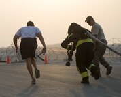 A firefighter with the Qatar Emiri Air Force Fire Department, Doha Air Base, drags a hose 150 feet during a firefighter combat challenge at Al Udeid Air Base, Qatar, Sept. 1, 2017.