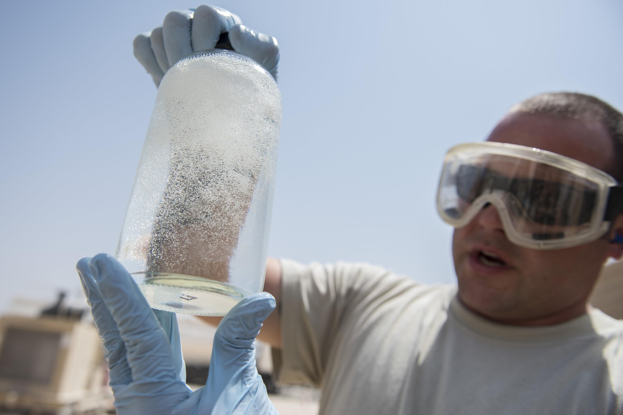 Tech. Sgt. Alex Johnson, 332nd Expeditionary Logistics Readiness Squadron fuels flight lab technician, looks at a sample of fuel from a truck delivery July 22, 2017, in Southwest Asia. The clear container allows Johnson to see if the sample is clean. (U.S. Air Force photo/Senior Airman Damon Kasberg