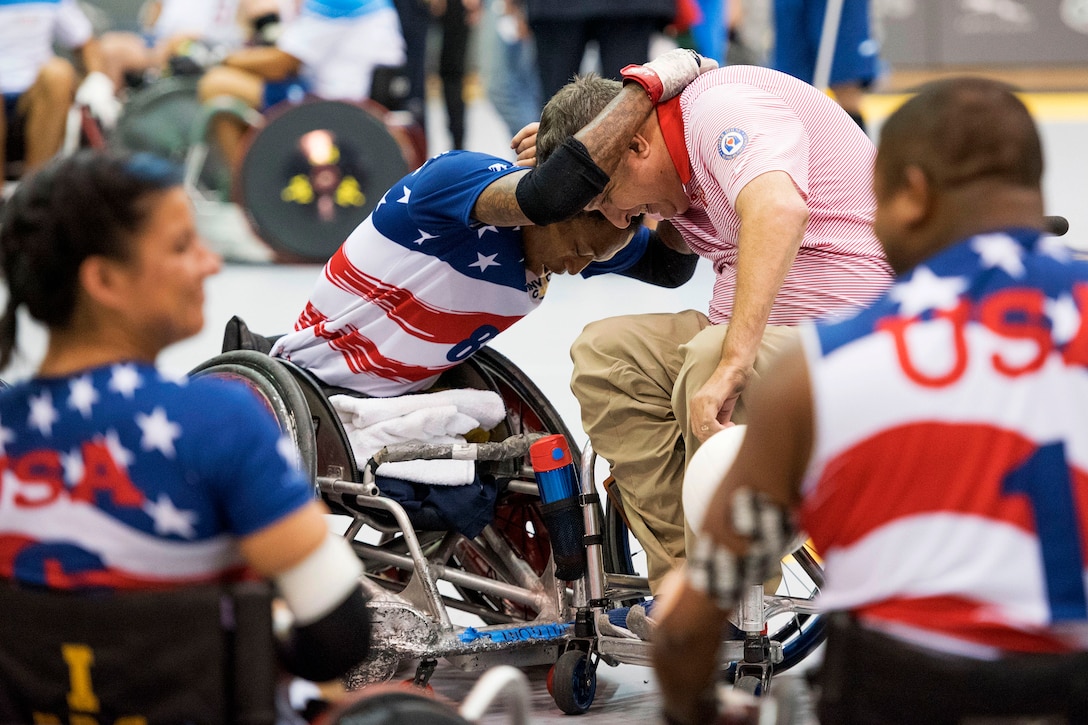 A player in a wheelchair hugs a coach also sitting in a wheelchair.