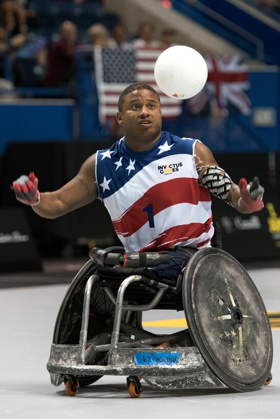A player in a wheelchair reaches for a ball in the air.