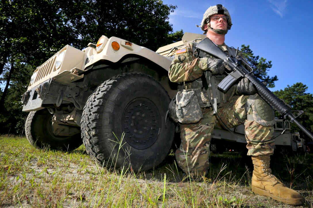 Army National Guard Sgt. Mark Gartner provides security next to a Humvee while on a field training exercise.