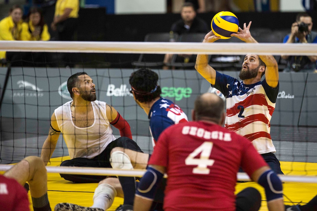 A player sitting on the ground hits a volleyball.