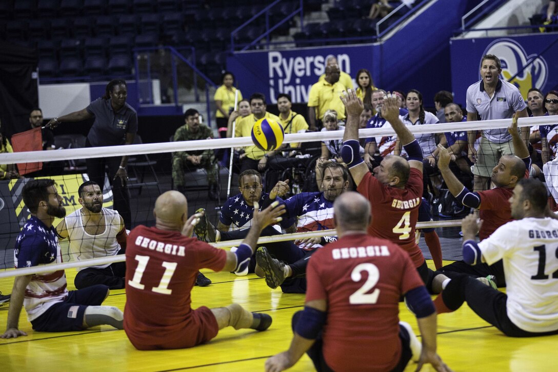 Players sit on the ground playing volleyball.