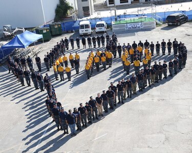 Chief petty officers past and present in blue T-shirts form an outline of Texas surrounding chief selectees in gold T-shirts during a CPO Pride event at VFW Post 76 in downtown San Antonio Sept. 8.