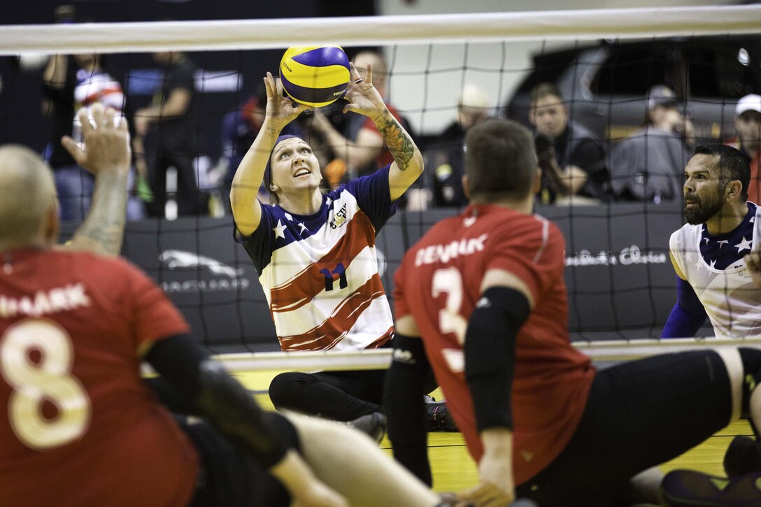 A player sitting on the ground hits a volleyball.