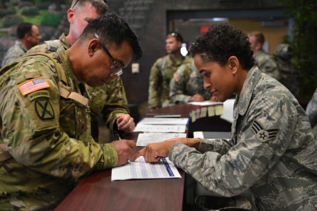 Two military members look at paperwork over a counter.
