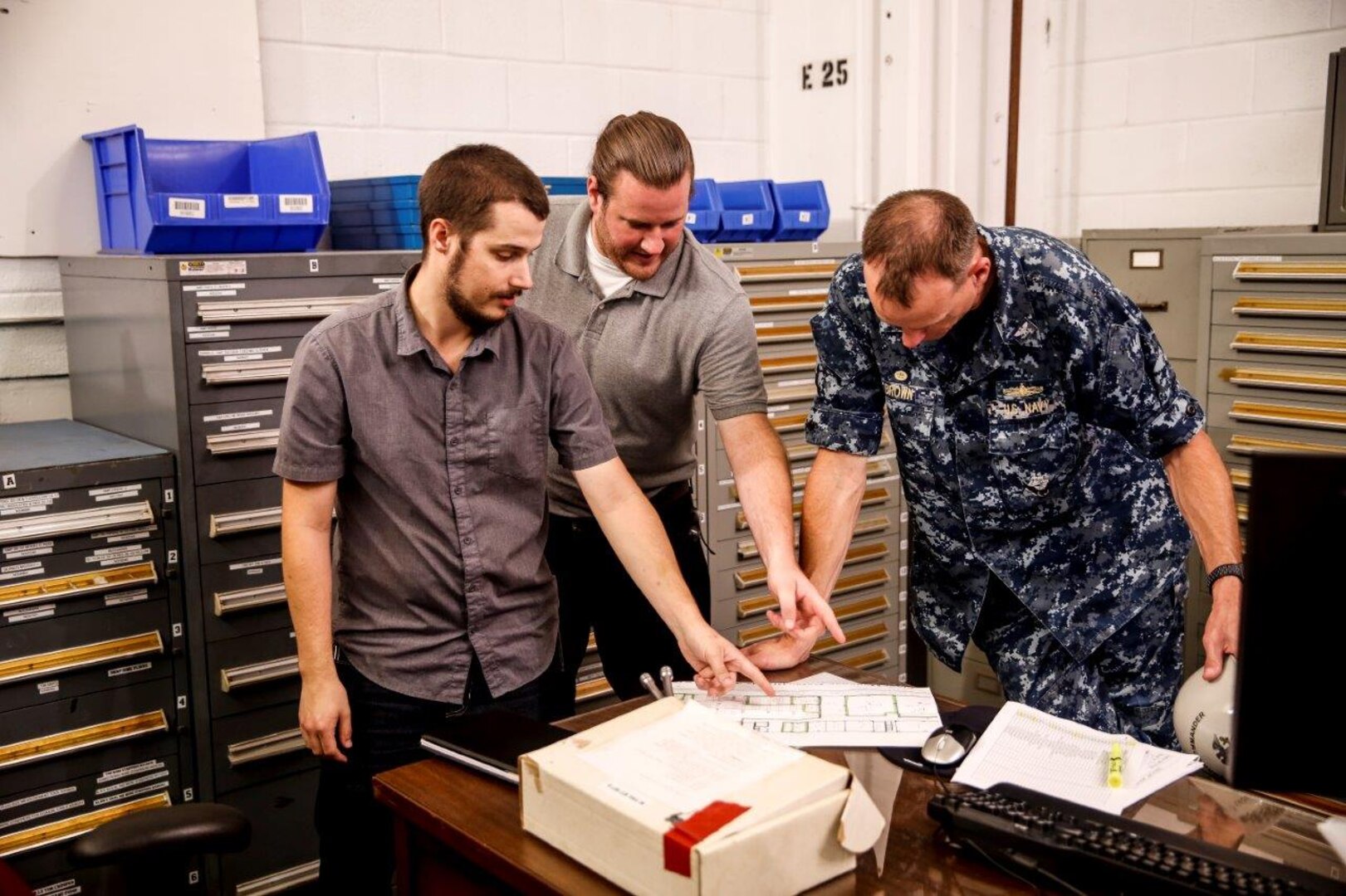 Image: Norfolk Naval Shipyard employees William Divers and Benjamin Kreps show shipyard commander Capt. Scott Brown the consolidated tool storage space intended to improve efficiency and maximize efficient use of shipyard workers' time.