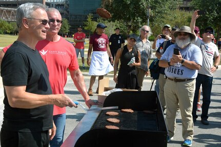Gary Sinise flips hamburgers as celebrity chef Robert Irvine and the crowd looks on during the Invincible Spirit Festival Sept. 15 at Brooke Army Medical Center. Sinise and Irvine have visited BAMC five times to put on the event, which features food, music and activities for BAMC staff, patients and family members.