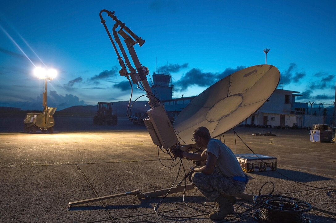 Staff Sgt. Trevor Black checks wires on a satellite communication antenna.
