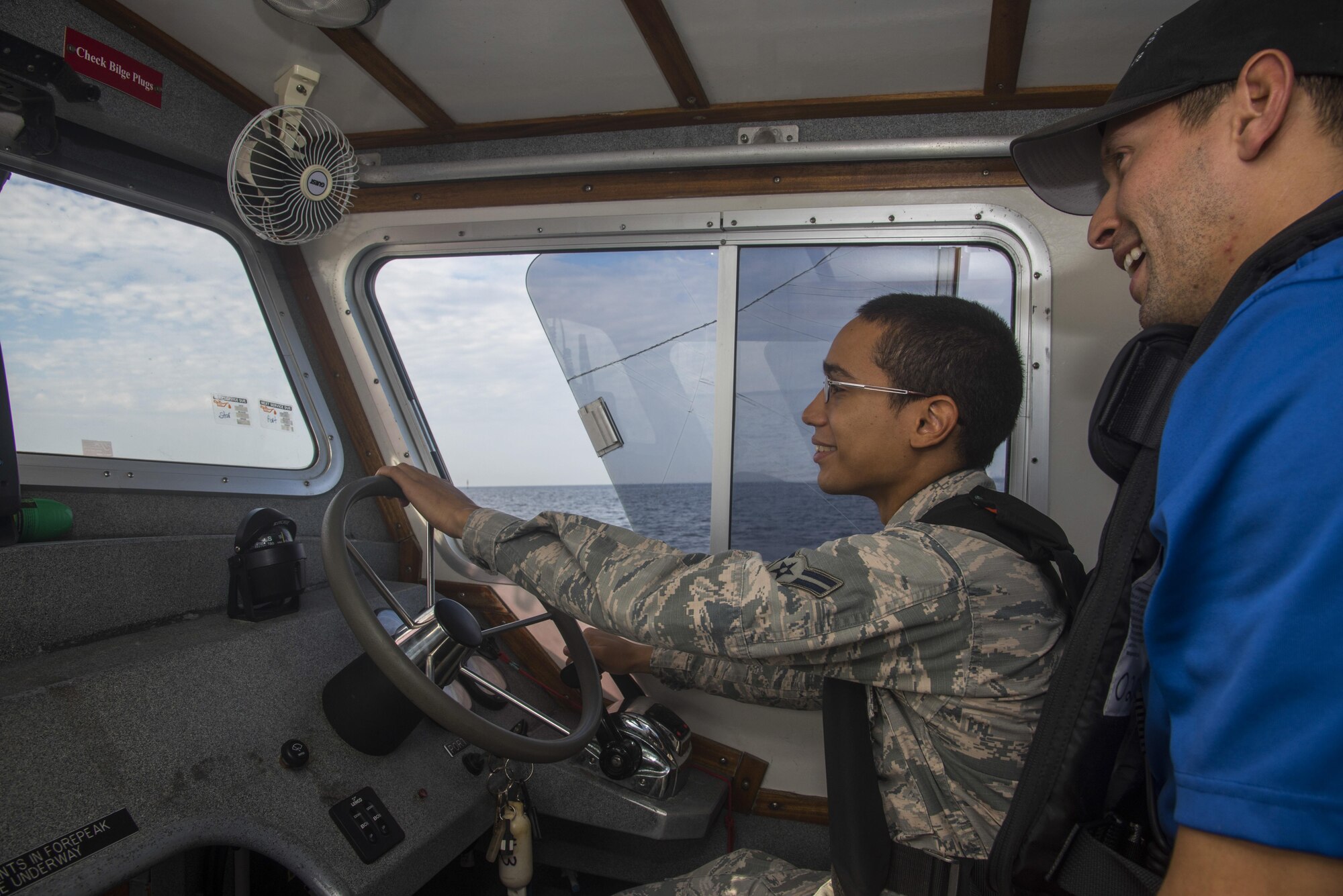 U.S. Air Force Staff Sgt. Kevin Gonzalez, a marine patrol crew lead assigned to the 6th Security Forces Squadron, right, teaches Airman 1st Class Jose Torres, a customer service technician assigned to the 6th Force Support Squadron, how to drive a patrol boat at MacDill Air Force Base, Fla., Sept. 21, 2017.