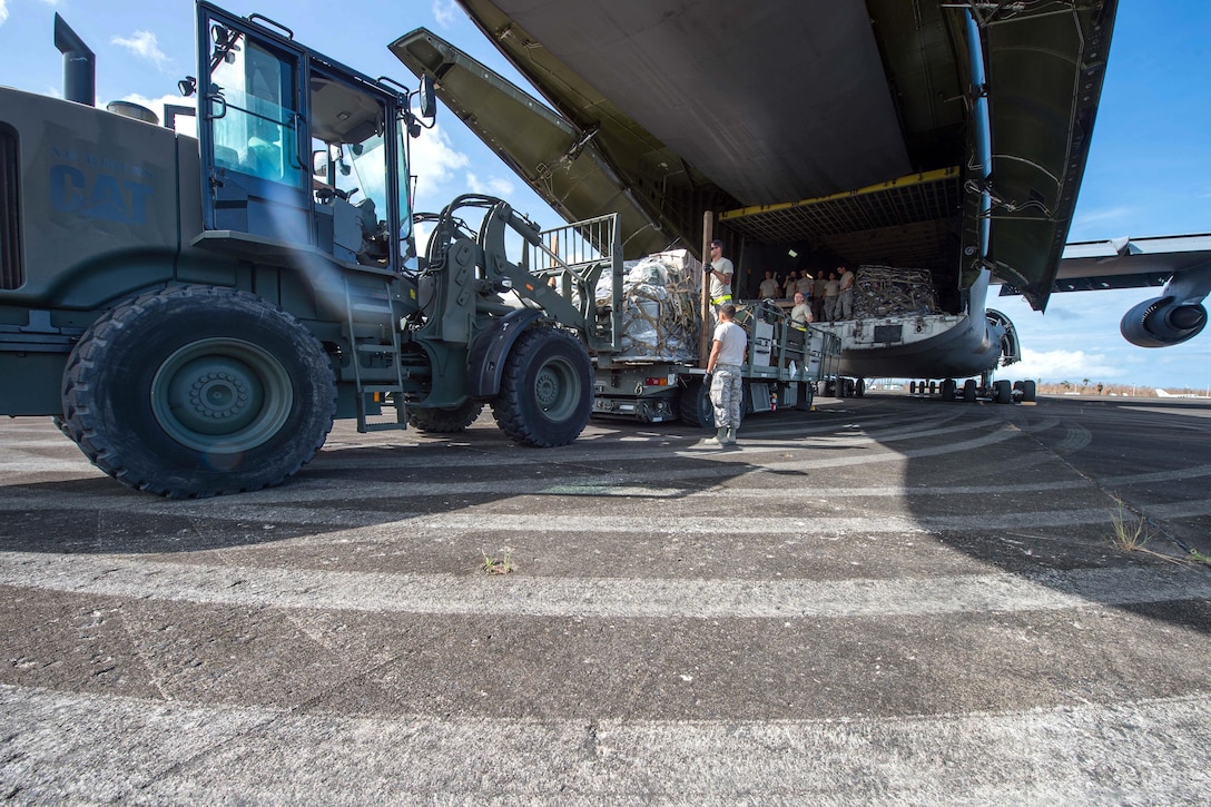 Airmen unload their equipment from a C-5M Super Galaxy aircraft.