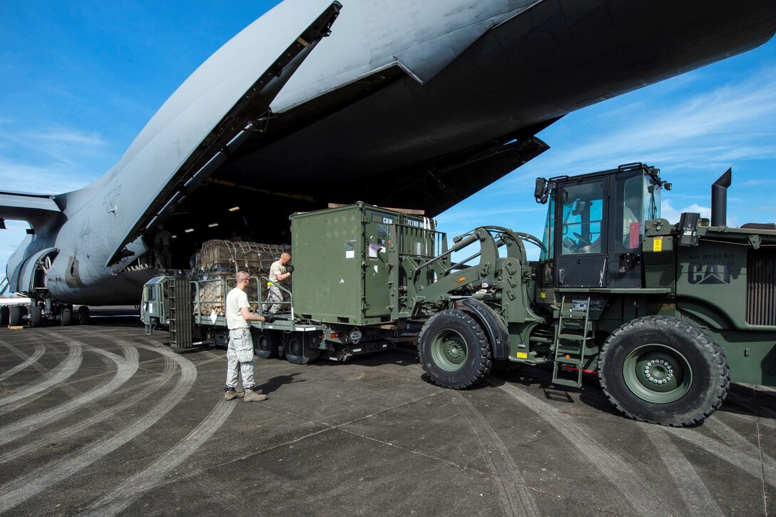Airmen offload their equipment from a C-5M Super Galaxy aircraft.