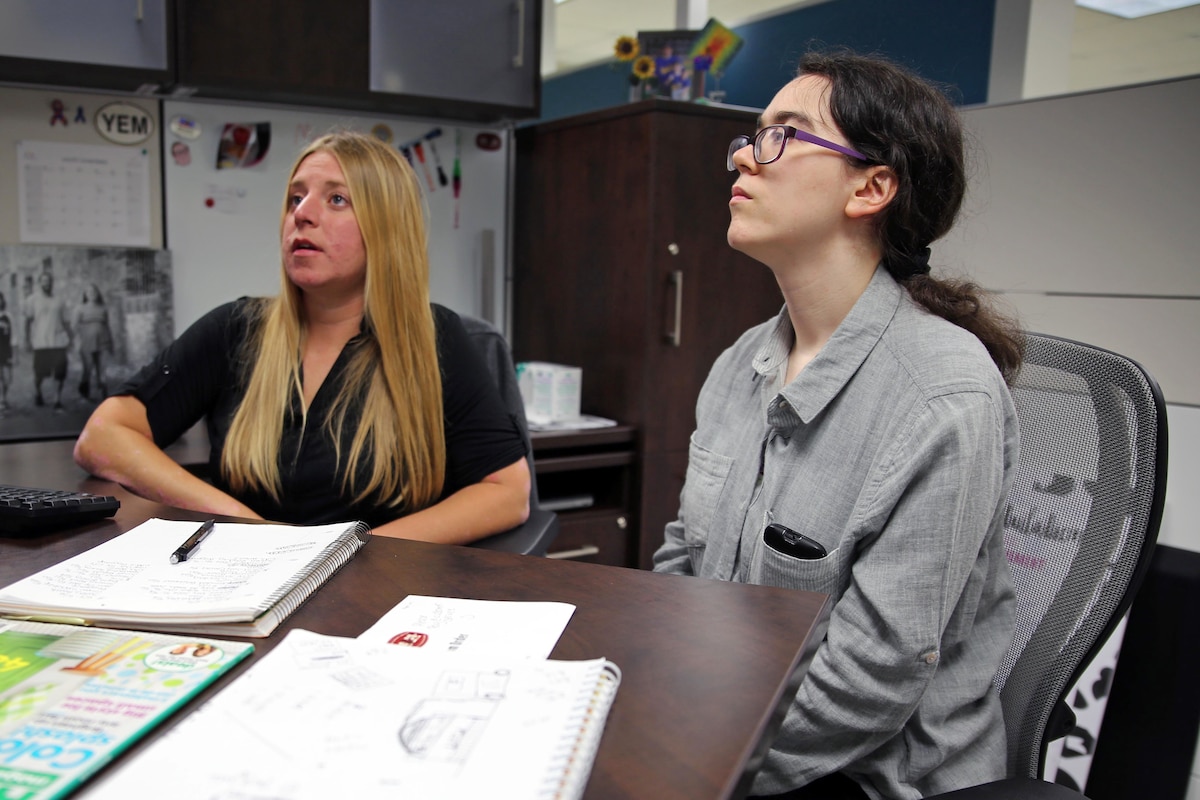 Two people who are seated look up at a screen that is not shown.