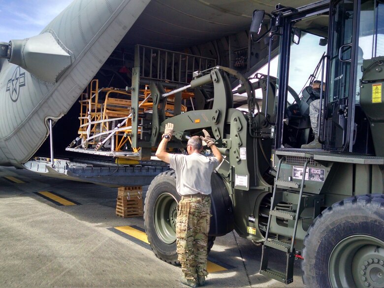 A 302nd Airlift Wing loadmaster guides a cargo load onto an Air Force Reserve Command C-130 Hercules aircraft Sept. 25, at the San Juan International Airport, Puerto Rico.