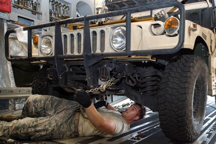 Senior Airman Nicholas Ezzo unchains a Humvee from a C-17 Globemaster lll aircraft.