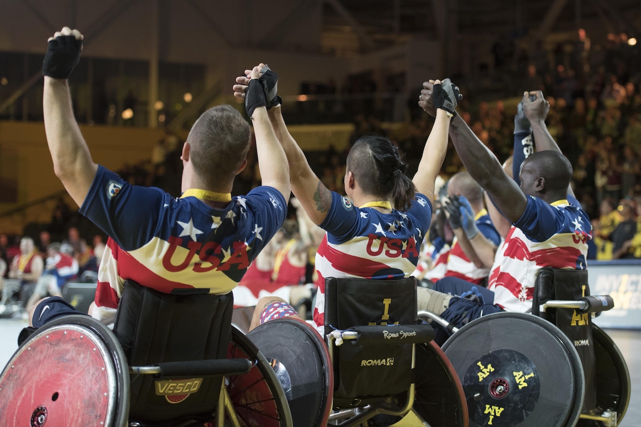 Left to right: Air Force veteran Master Sgt. Jesse Graham, Air Force veteran Staff Sgt. Sebastiana Lopez-Arellano and Army veteran Army Cpt. William Reynolds join hands with the rest of the U.S. wheelchair rugby team after receiving bronze medals during the 2017 Invictus Games at the Mattamy Athletic Centre in Toronto, Sept. 28, 2017. The Invictus Games, established by Prince Harry in 2014, brings together wounded and injured veterans from 17 nations for 12 adaptive sporting events, including track and field, wheelchair basketball, wheelchair rugby, swimming, sitting volleyball, and new to the 2017 games, golf. DoD photo by Roger L. Wollenbe
