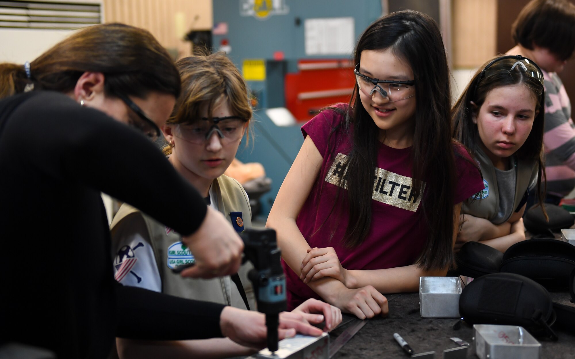 Girl Scouts from Troop 50 watch their troop leader punch a hole in a metal box during a maintenance tour at Osan Air Base, Republic of Korea, Mar. 28, 2018.