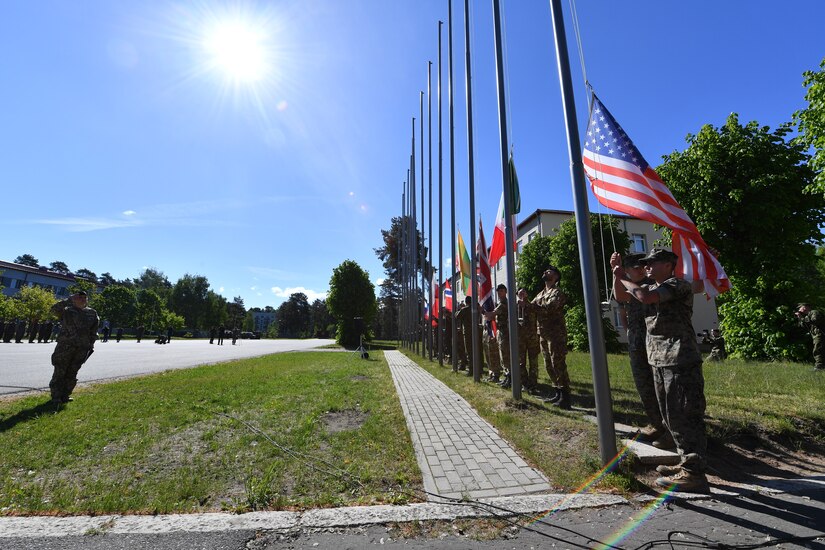 U.S. and NATO military members raise their countries’ flags during the opening ceremony for exercise Saber Strike