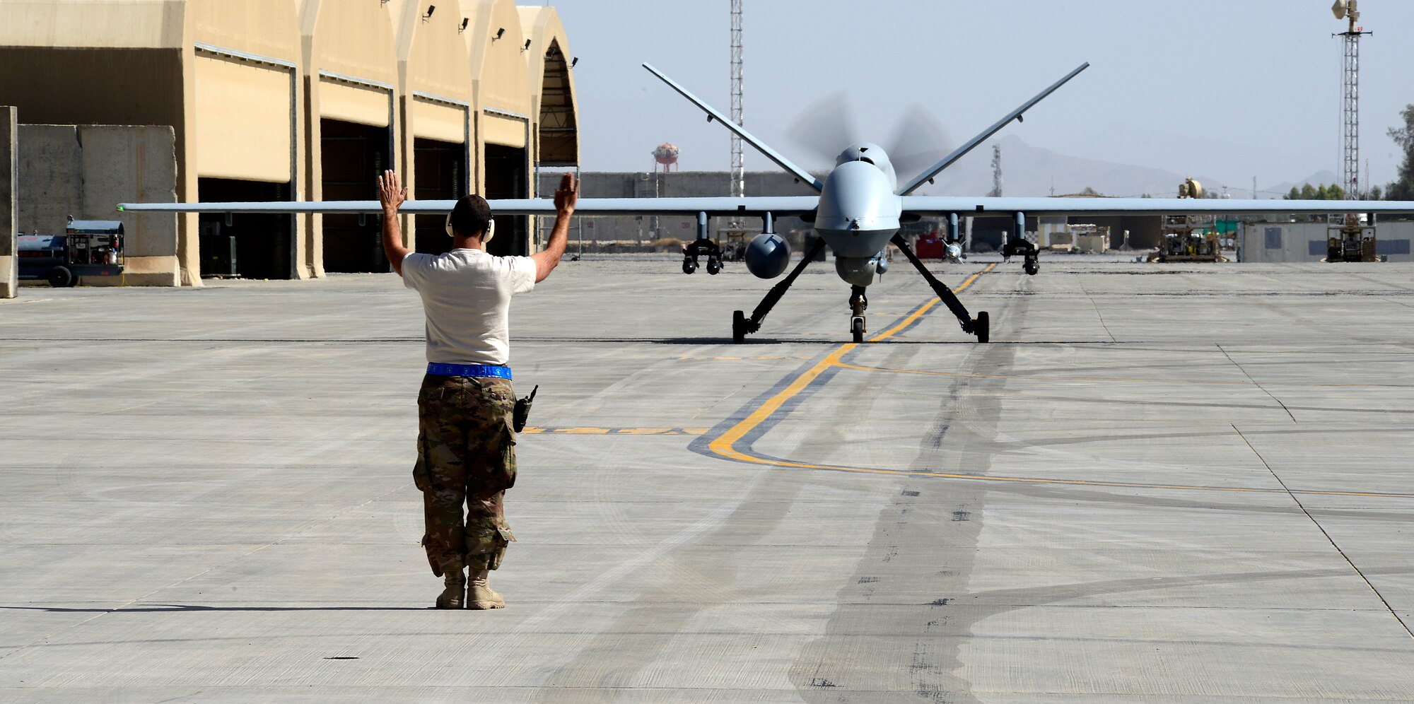 An Airman assigned to the 451st Expeditionary Aircraft Maintenance Squadron marshals an MQ-9 Reaper to its parking spot, March 23, 2018, at Kandahar Airfield, Afghanistan.