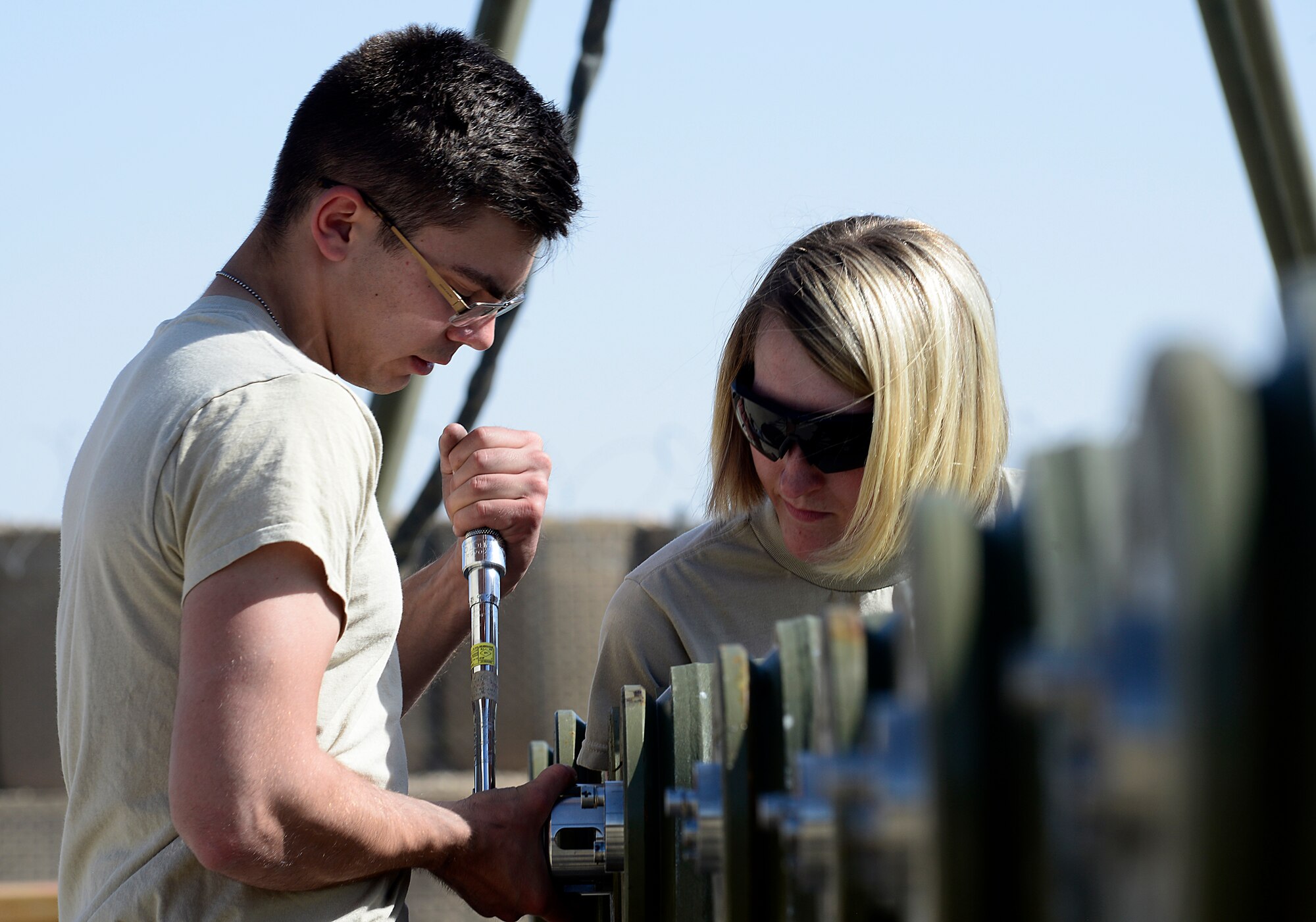 Senior Airman Ethan Dietz and Staff Sgt. Amanda Loyd, 451st Expeditionary Aircraft Maintenance Squadron conventional maintenance crew members, torque a closure ring on the tail fuse of a GBU-38 version one, March 23, 2018, at Kandahar Airfield, Afghanistan.