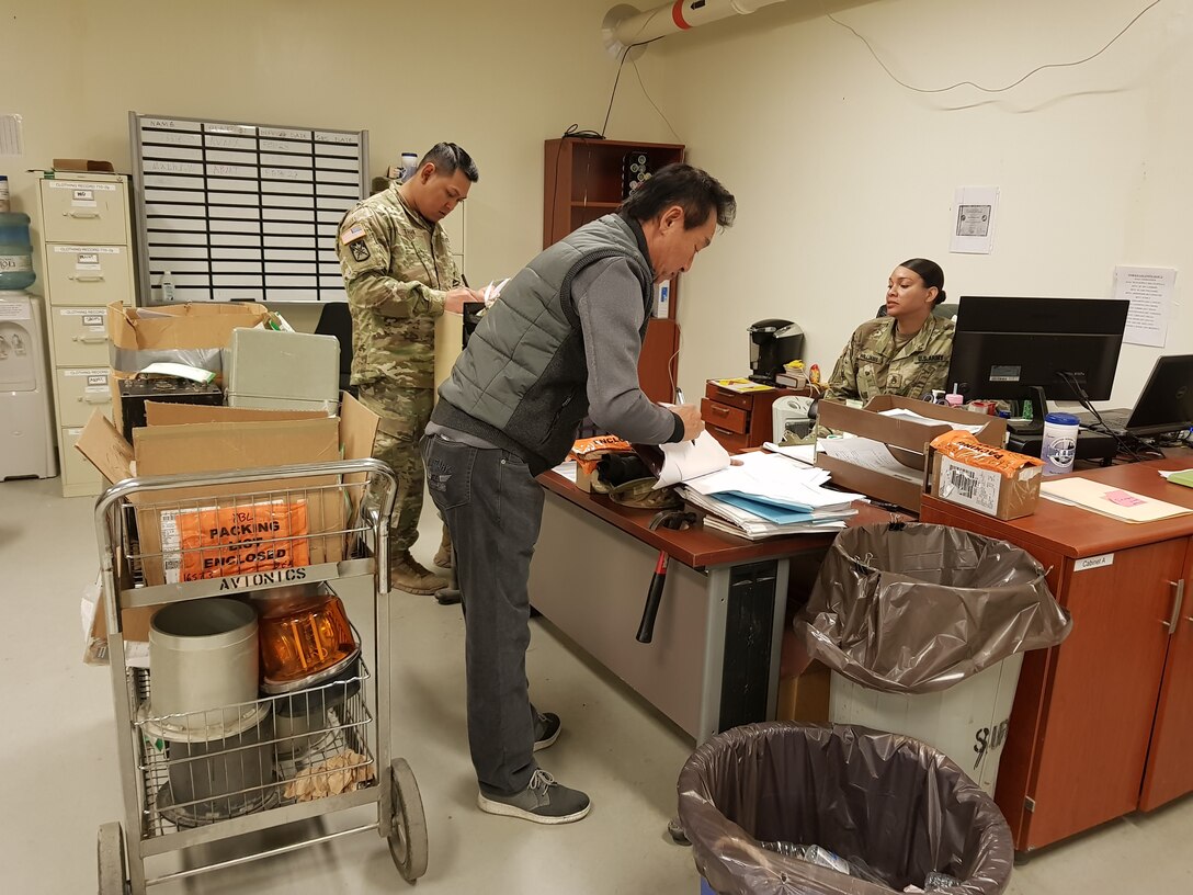 Team member Ki Song Chong (center) educates Army Sgt. John Than (left) and Staff Sgt. Gena Williams from the 602nd Aviation Support Battalion on the proper use of local stock numbers for items that do not have National Stock Numbers.