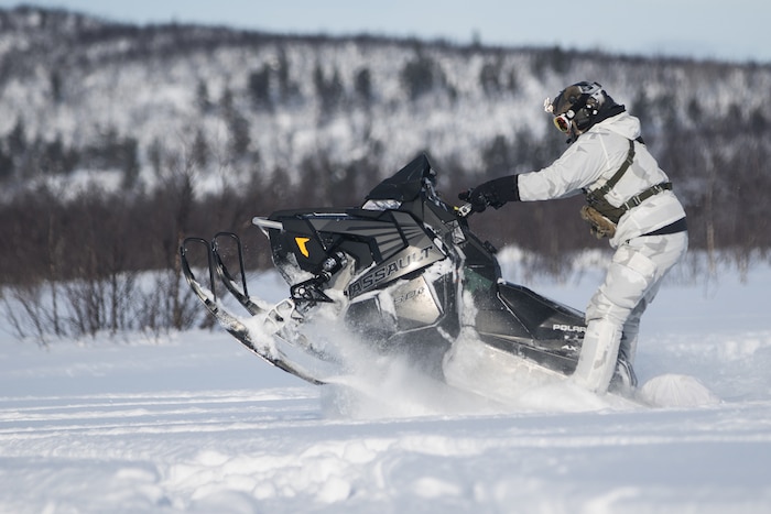 A soldier rides a snowmobile.