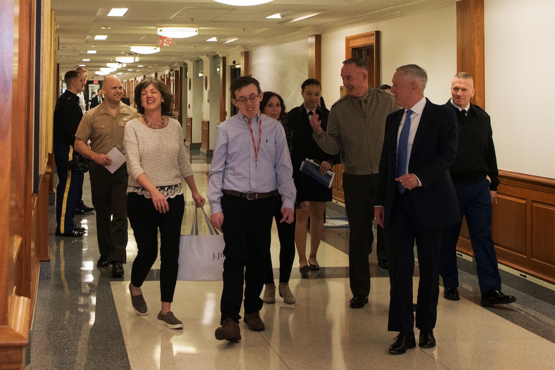 Defense Secretary James N. Mattis; Marine Corps Gen. Joe Dunford, chairman of the Joint Chiefs of Staff; and Army Command Sgt. Maj. John W. Troxell, the chairman's senior enlisted advisor, walk with a visitor in a Pentagon hallway.