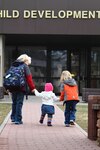 Three children make their way to a Child Development Center. Many service members take advantage of childcare services on base while they work.