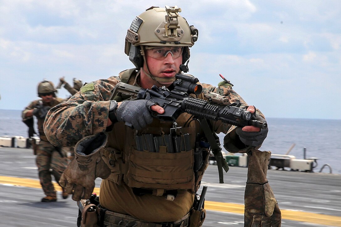 A Marine provides security while conducting fast-rope training.