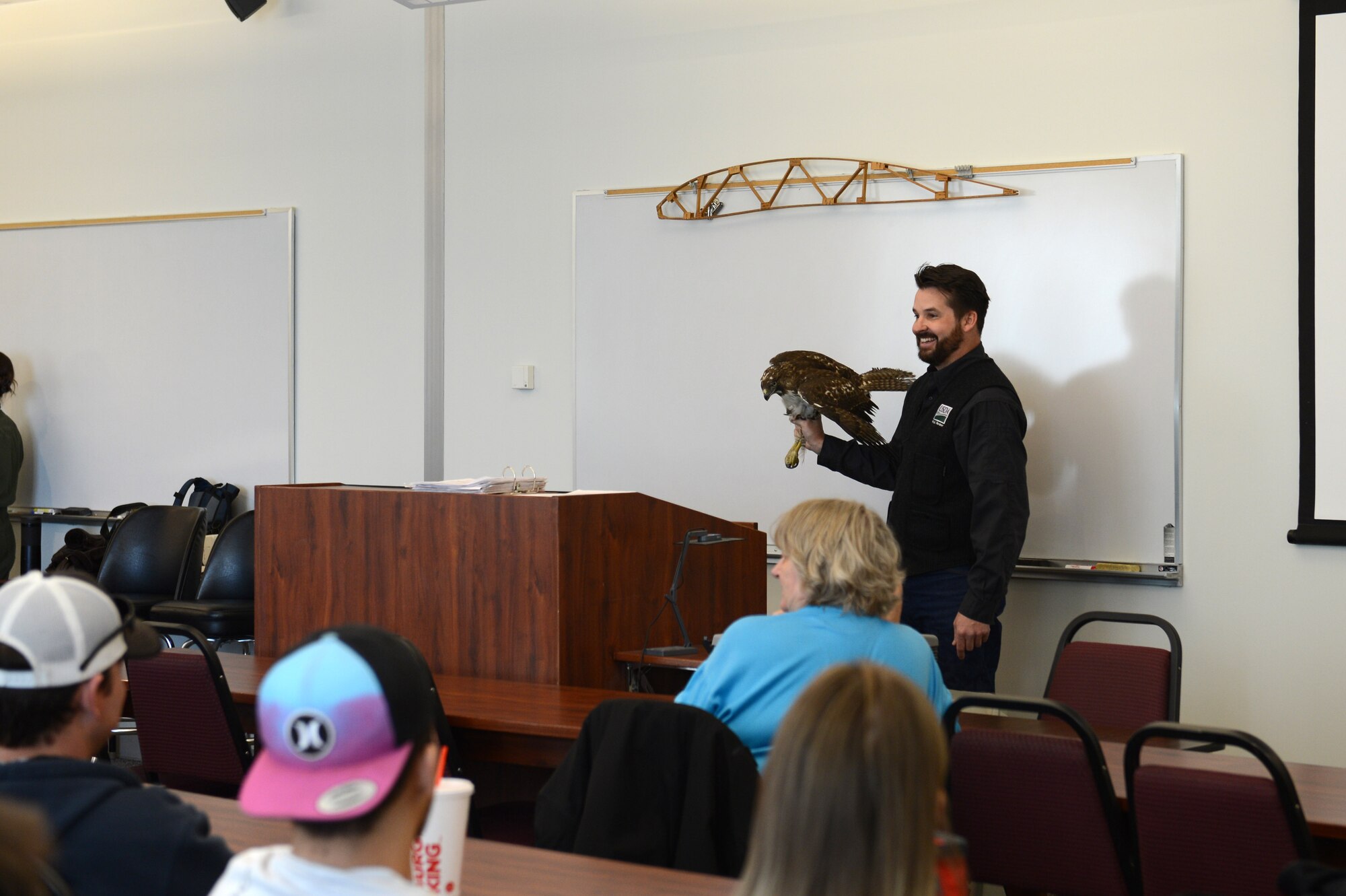 Laurence Schafer, USDA wildlife biologist with the bird and wildlife aircraft strike hazards (BASH) at McChord Field, holds a Red Tailed Hawk caught on the McChord Field flight line the previous day, during a lesson for Big Bend Community College pilot students about the way different types of birds interact with planes, March 16, 2018, at Moses Lake, Wash. Red Tailed Hawks, along with several other species of bird, are trapped on the flight line and relocated to prevent them being hit by planes.