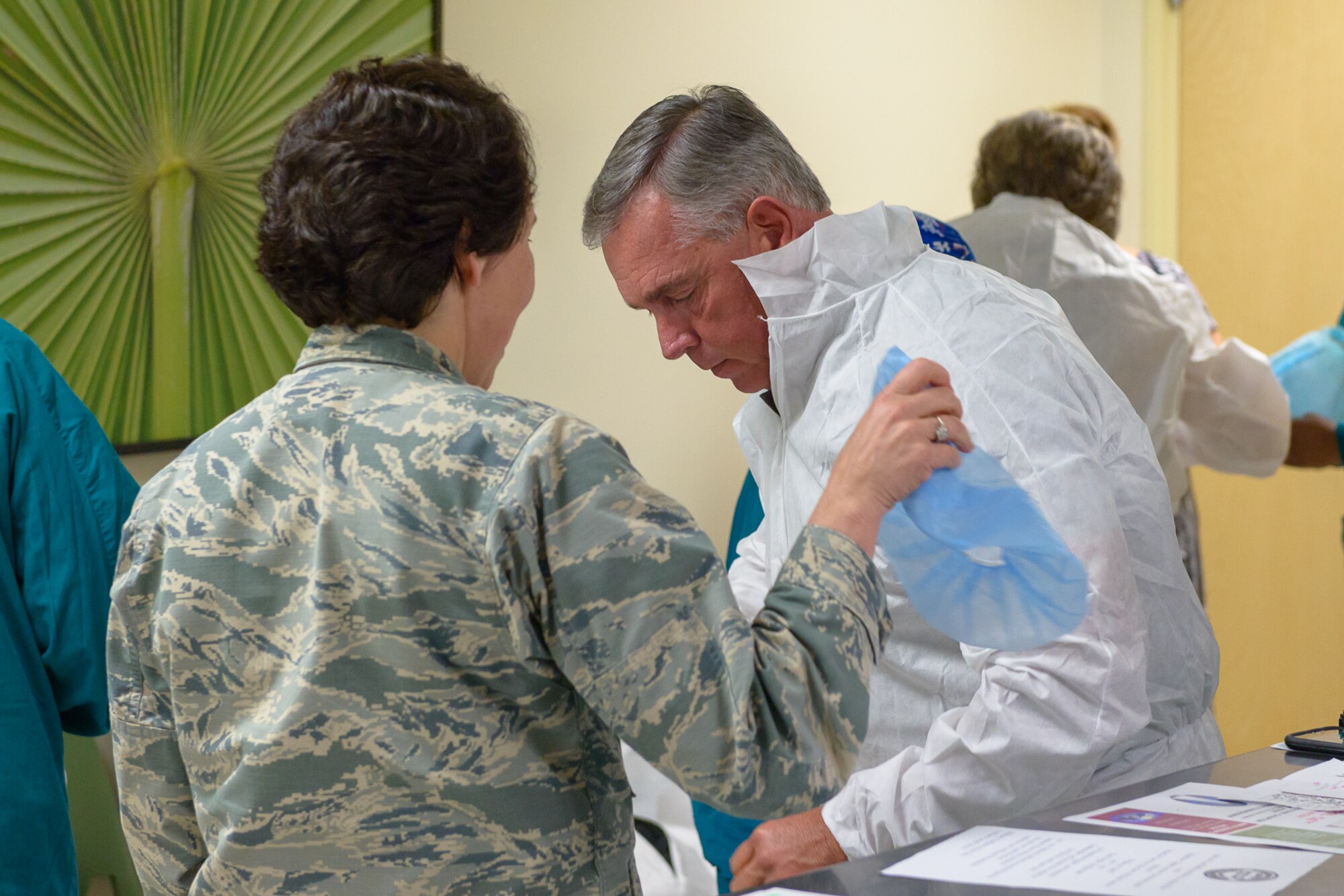 U.S. Air Force Col. Jeannine Ryder, 81st Medical Group commander, assists Jeff Hammond, with his protective clothing during a visit at Keesler Medical Center March 30, 2018, on Keesler Air Force Base, Mississippi. Hammond and Gant spent the day meeting veterans at the Armed Forces Retirement Home and toured various facilities that support veterans on Keesler Air Force Base. Gant is a former NASCAR driver and Hammond is a current TV broadcaster for the motorsport. (U.S. Air Force photo by Andre' Askew)