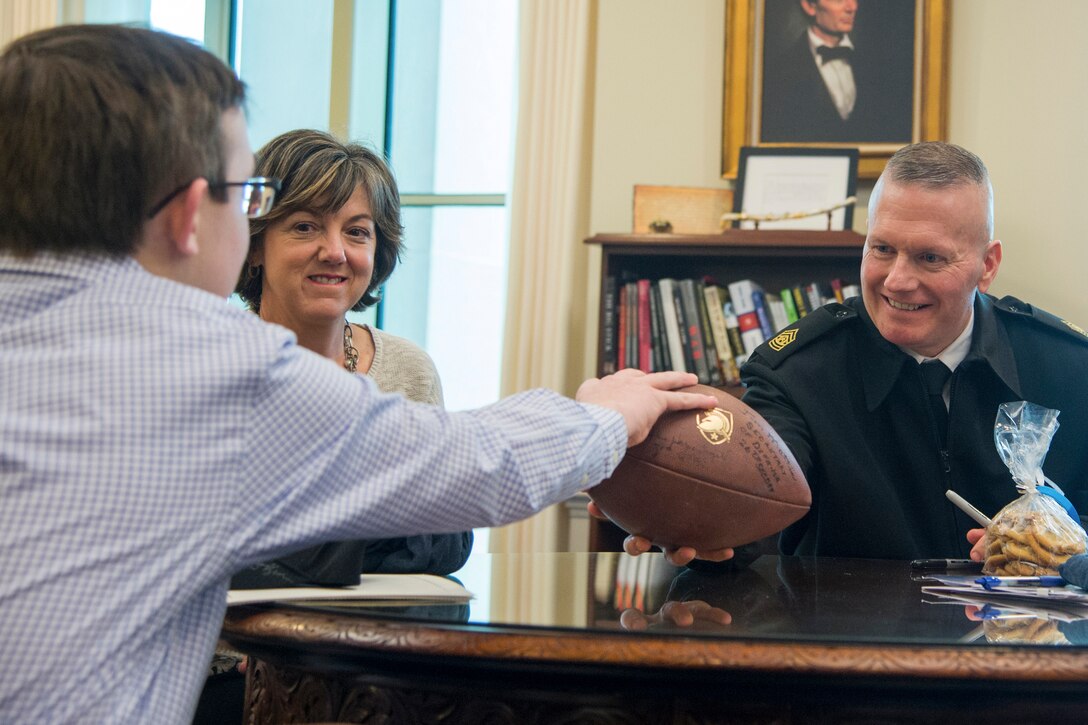 Army Command Sgt. Maj. John W. Troxell, senior enlisted advisor to the chairman of the Joint Chiefs of Staff, hands a football to a civilian