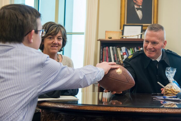 Army Command Sgt. Maj. John W. Troxell, senior enlisted advisor to the chairman of the Joint Chiefs of Staff, hands a football to a civilian
