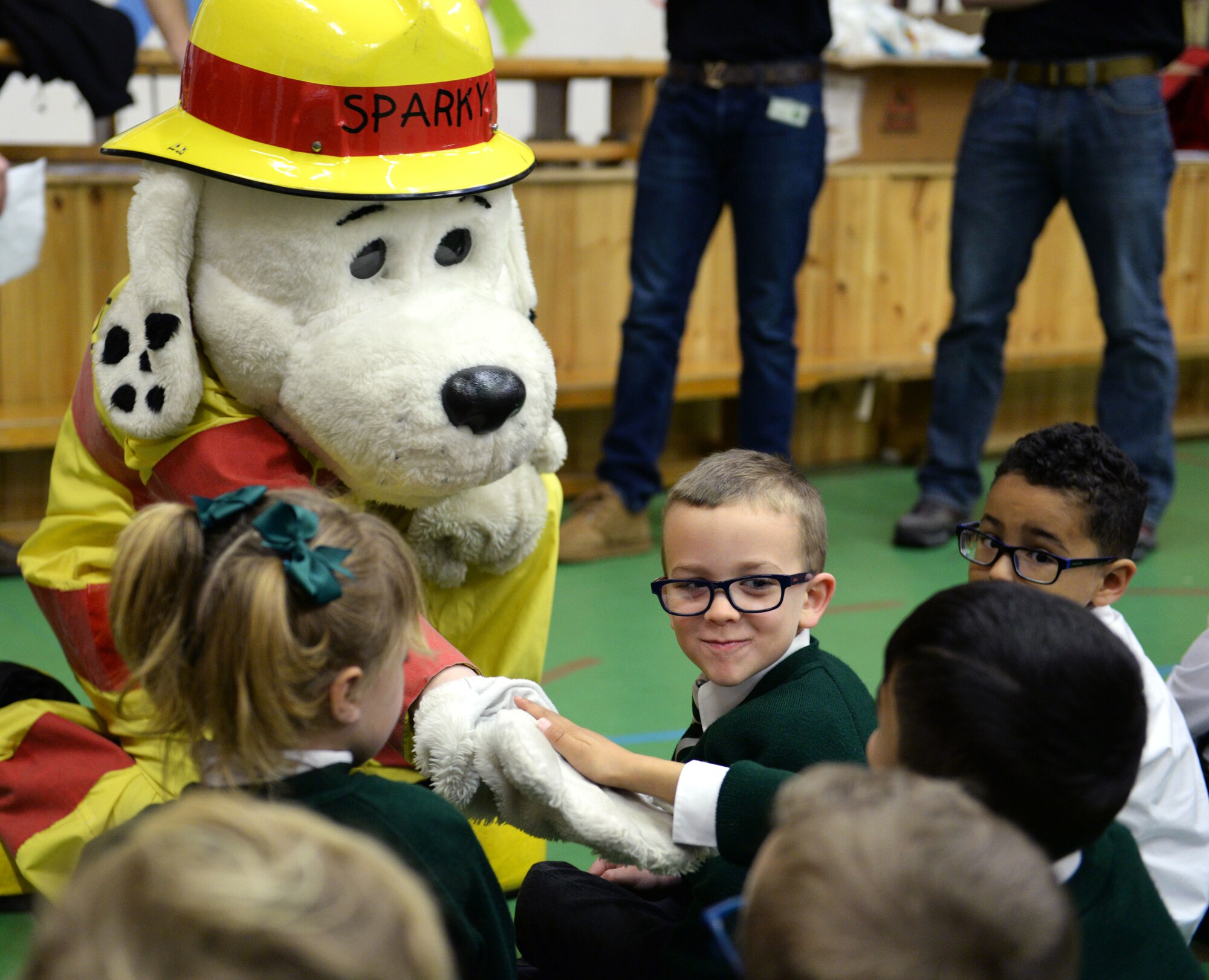 Sparky the Fire Dog, 100th Civil Engineer Squadron Fire Department mascot, greets young students from the Great Heath Academy in Mildenhall, England, March 27, 2018. The firefighters showed the children what their gear is used for, explained how it protects them, and allowed the children to try on the gear. (U.S. Air Force photo by Airman 1st Class Alexandria Lee)