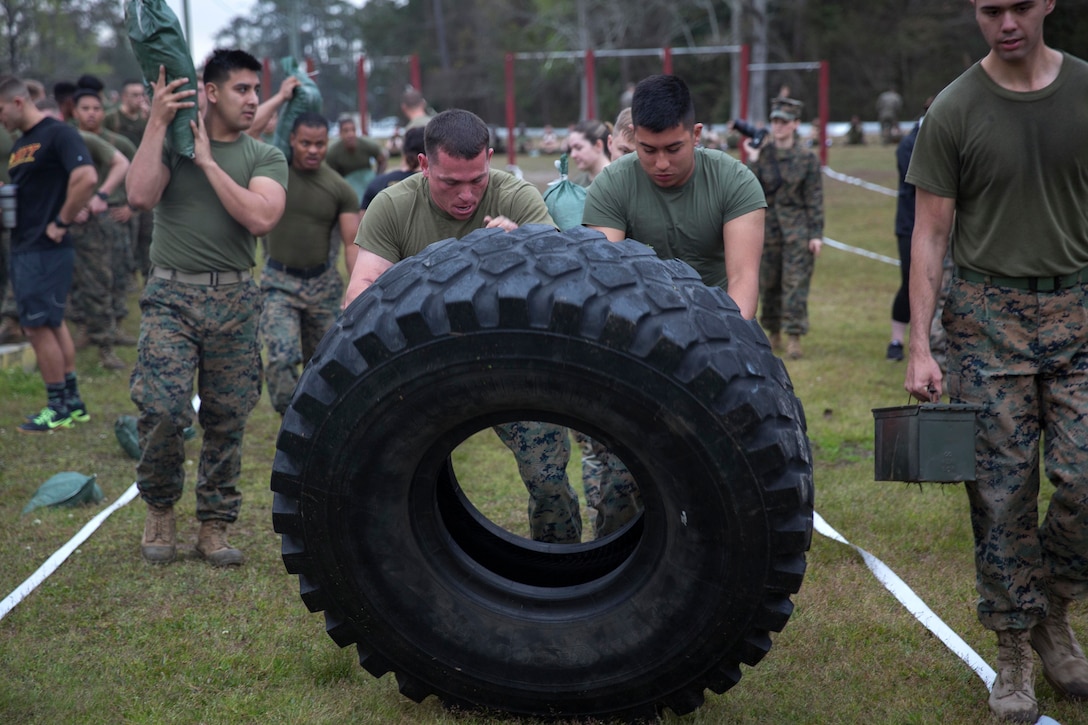 Marines and sailors perform a tire flip.